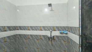 a shower in a bathroom with tiles on the wall at Aashirwad Residency Inn in Gaya +16 photos