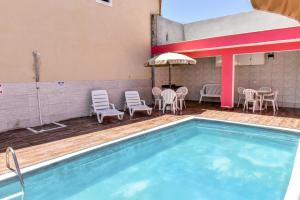 ein Pool in einem Hotel mit Stühlen und Tischen in der Unterkunft Chalés por temporada no Villagio Santa Mônica, em Caraguatatuba in Caraguatatuba