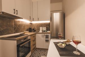 a kitchen with white cabinets and two glasses of wine at Victoria's Aura I in Kozani