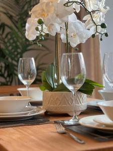 Una mesa con dos copas de vino y un jarrón con flores blancas. en Spacious 2 Bed, 2 Bath Apartment by MCF, en Horley