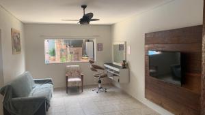 - un salon avec une télévision, une chaise et un bureau dans l'établissement Cantinho do Sossego, à Olímpia