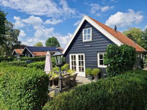a blue house with a patio and an umbrella at d'Oude Herbergh, vakantiehuizen aan het water in Terherne