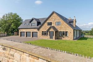 a large brick house with a stone wall at Northern Hideaways Oakfield Lodge, Ponteland in Newcastle upon Tyne