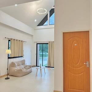 a living room with a couch and a wooden door at Prangsirihome guesthouseได้ทั้งหลัง in Lampang +6 photos