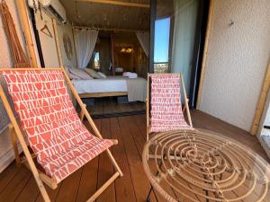 two chairs and a table on a porch with a bed at Barcazen in Le Barcarès