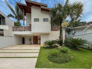 a house with a palm tree in front of it at Casa Luna - Elegante c/ Enxoval Completo - Riviera in Riviera de São Lourenço