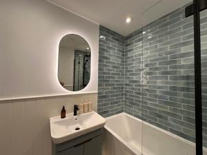 a bathroom with a sink and a mirror and a tub at Lobbs Cottage, St Mawgan in Saint Mawgan