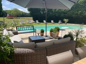 a patio with a couch and an umbrella and a pool at Fonsegre Chambres d'Hôtes in Magny-Cours
