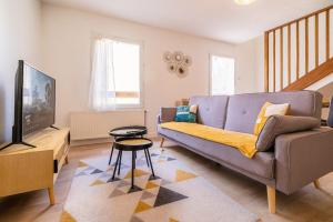 Una sala de estar con un sofá y un televisor. en Le Petit Nid en Haut, en duplex, en Limoges