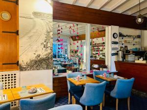 a restaurant with blue chairs and tables and a beach at Hôtel de la Plage in Fécamp