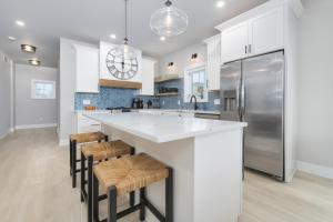 a kitchen with a large white island with bar stools at Toes in the Water , pool , perfect for large groups in South Haven