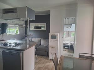 AzurLandes Azur mobil home 38 m2 7km de vieux boucau的厨房以及带炉灶和沙发的客厅。 更多13张照片