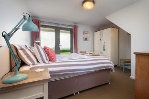 a bedroom with a bed with a blue lamp on a desk at Sloopside Main House in the heart of Bantham with sea views in Bantham