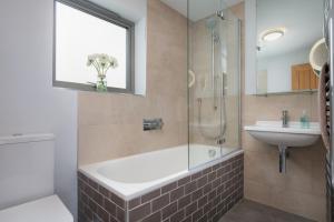 a bathroom with a tub and a sink and a shower at Sloopside Main House in the heart of Bantham with sea views in Bantham