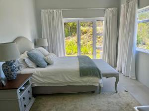 a white bedroom with a bed and a window at The Pijper House - Brackenridge Eco Estate Plettenberg Bay in Plettenberg Bay +47 photos