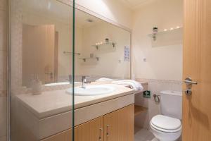 a bathroom with a sink and a toilet and a mirror at Vista Das Ondas 308 By RS in Olhos de Água +9 photos
