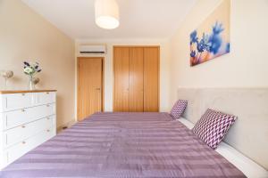 a bedroom with a bed with a purple blanket at Vista Das Ondas 308 By RS in Olhos de Água
