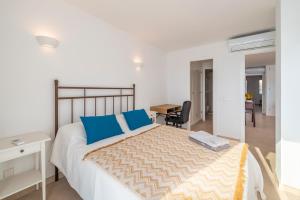 a bedroom with a bed with blue pillows and a desk at Windsong in Port de Pollensa