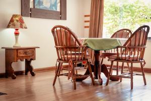 a dining room table with three chairs and a table with a lamp at Hotel Geneve - 2km do Capivari in Campos do Jordão +20 photos