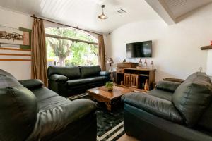 a living room with two leather couches and a table at Hotel Geneve - 2km do Capivari in Campos do Jordão