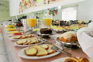 a buffet line with different types of bread and pastries at Hotel Geneve - 2km do Capivari in Campos do Jordão
