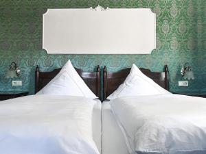 due letti bianchi in una camera da letto con carta da parati verde di Hotel Schloss Ysenburg a Staden Altre 4 foto