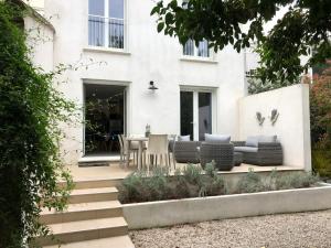 Dieses weiße Haus verfügt über eine Terrasse mit einem Tisch und Stühlen. in der Unterkunft Maison 3 chambres, Parking, jardin, climatisation in Arles