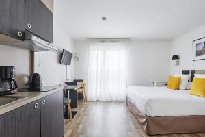 a hotel room with a bed and a kitchen with a sink at Appart'hôtel Odalys City - Paris Levallois in Levallois-Perret