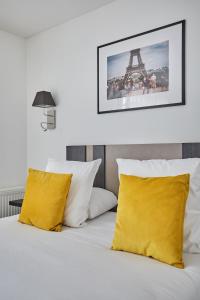ルヴァロワ・ペレにあるAppart Hotel Odalys City Paris Levalloisの黄色い枕とエッフェル塔付きのベッド +37枚の写真