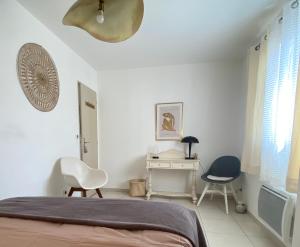 ein Schlafzimmer mit einem Bett und zwei Stühlen und einem Schreibtisch in der Unterkunft Maison 3 chambres, Parking, jardin, climatisation in Arles