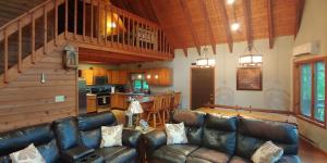 a living room with a leather couch and a kitchen at Pocono Mountain Retreat in Cresco