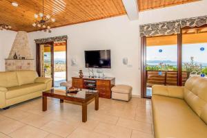a living room with a couch and a tv and a table at Sunset View Villa in Argaka