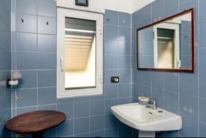 La salle de bains est pourvue de carrelage bleu, d'un lavabo et d'un miroir. dans l'établissement Rustico tra gli Ulivi, à Rapallo