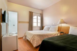 a hotel room with two beds and a television at Hotel Geneve - 2km do Capivari in Campos do Jordão