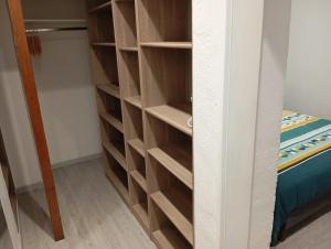 a closet with wooden shelves next to a bed at Grand Studio chambre séparée in Arpajon-sur-Cère +10 photos