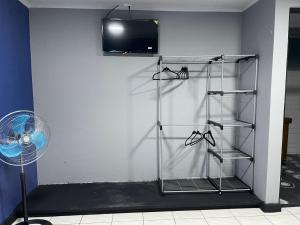 a room with a white wall with a fan and a shelf at la casona rio in Alajuela