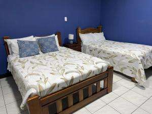 two beds in a bedroom with blue walls at la casona rio in Alajuela