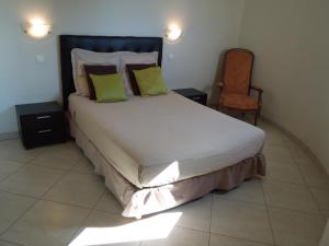 a bedroom with a large bed and a chair at Résidence BELLA VISTA in Santa-Maria-di-Lota