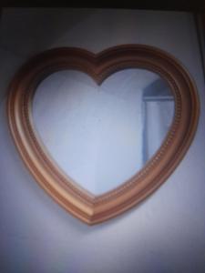 a heart shaped mirror with a wooden frame on a wall at Casa vacanze Eugenia in Ragusa +19 photos