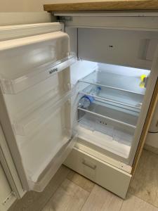 an empty refrigerator with its door open in a kitchen at KOMFORT FerienWohnung NeuBau Merzig in Merzig
