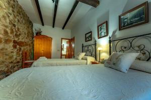 a bedroom with two beds and a stone wall at El Cerrillo in Navaconcejo
