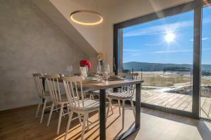 a dining room with a table and chairs and a large window at Sunset Apartments in Kovářov