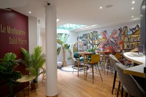 a restaurant with chairs and tables and a mural at Hôtel Le Montmartre Saint Pierre in Paris