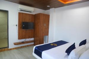 a bedroom with a bed with a tv on the wall at Cosmos Resort Maliblu in Indore