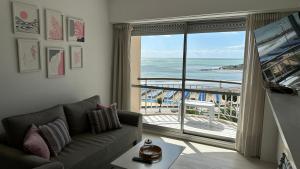 a living room with a couch and a view of the ocean at Depto Varese - Depto Vista al Mar Zona Varese Para 3 PAX Con Cochera - Hola Sur in Mar del Plata +4 photos