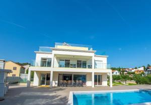 a large white house with a swimming pool in front of it at Villa Anto in Pridraga