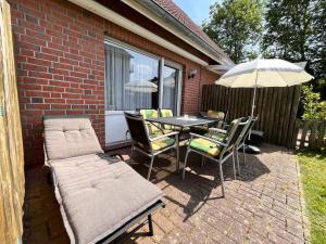 a patio with a table and chairs and an umbrella at Ferienhaus Veldhoen in Norddeich