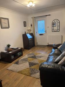 a living room with a leather couch and a tv at Black Bull Barn in Kirkby Stephen