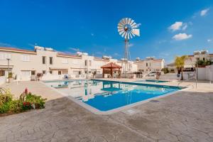 a swimming pool with a windmill in the background at Villa Poppy in Paralimni