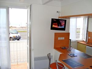 a kitchen with a desk and a television on the wall at APPARTEMENT FACE MER T2 35 m2 pour 4 personnes proche tous commerces in Saint-Jean-de-Monts